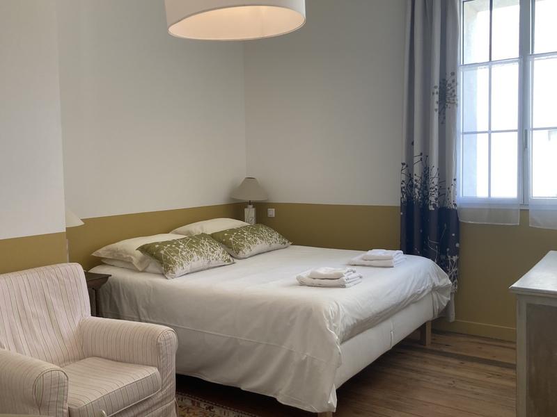 Chambre avec un lit double, un fauteuil.
