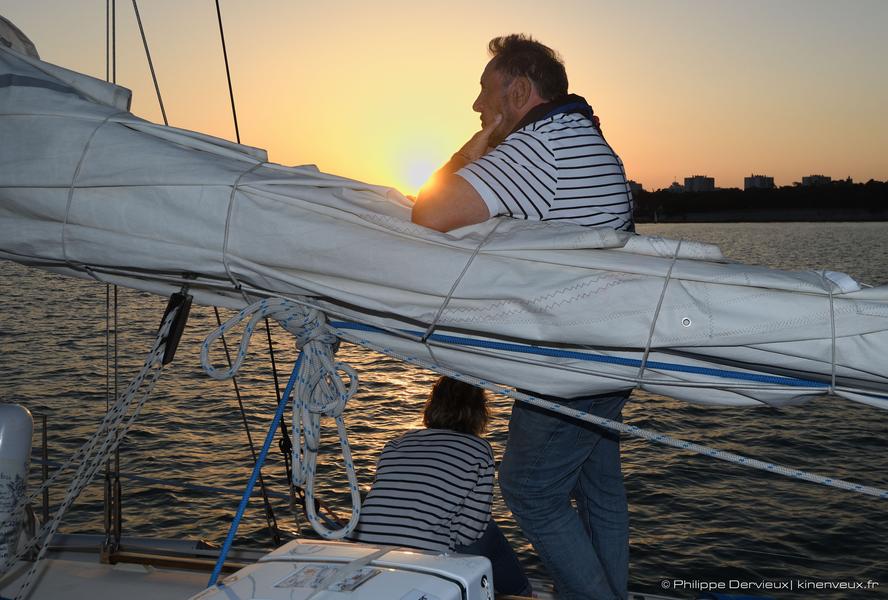 Passagers regardant l'océan sous la lumière su soir