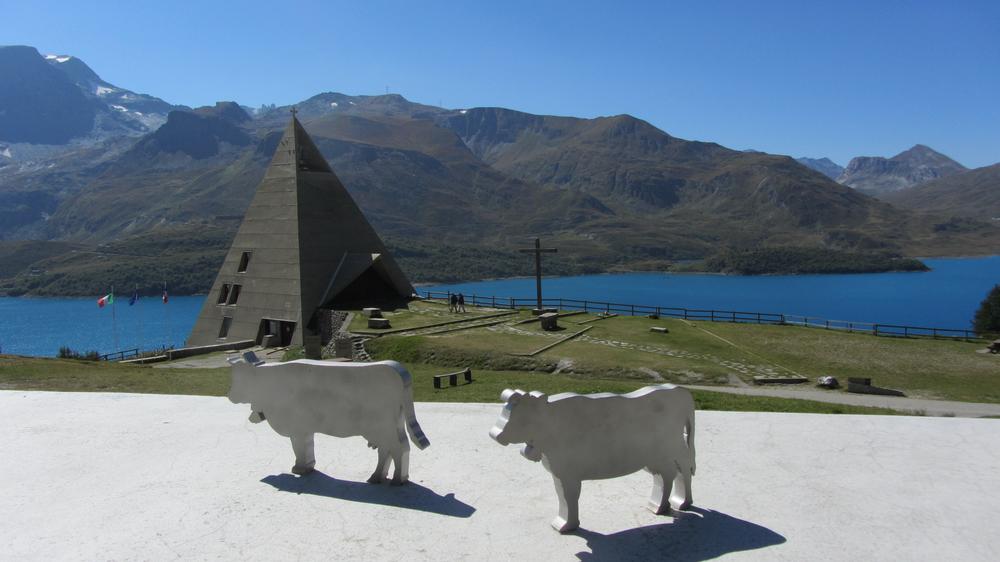 Vache en métal en premier plan avec la pyramide du Mont-Cenis en second plan et le lac au loin