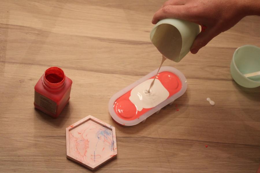 Une main faisant un mélange de couleurs crème et orange