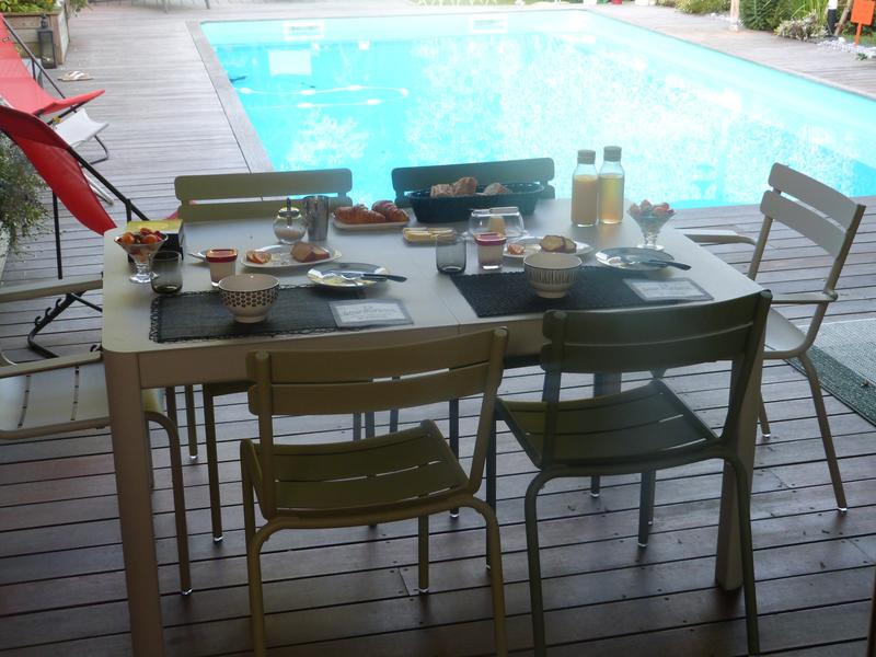 La table dressée pour un petit-déjeuner pour 4 personnes, à côté de la piscine.
