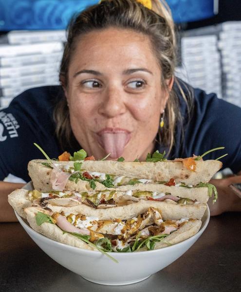 Sabrina tire la langue devant des pizzas