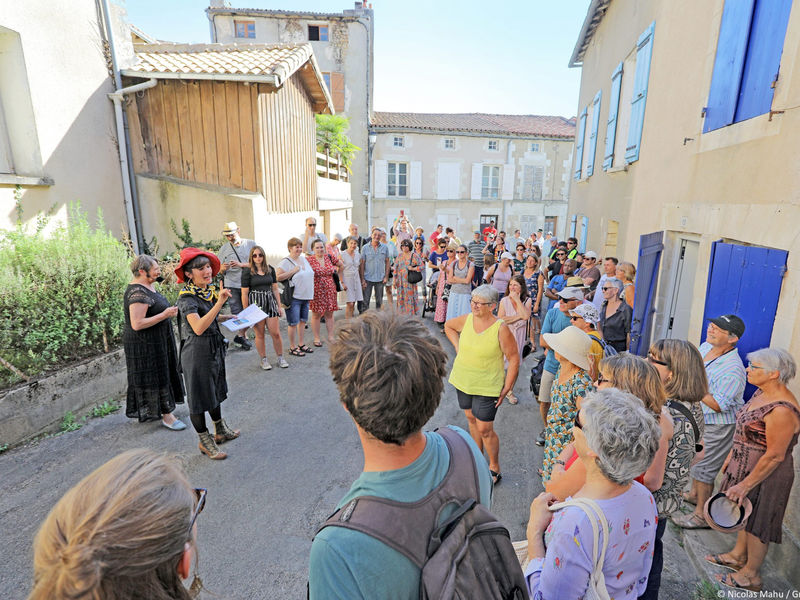 Spectateurs suivant une visite insolite dans les rue dun village