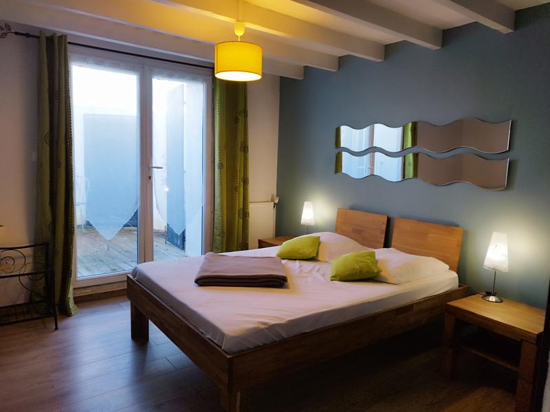Une chambre avec un lit double, porte-fenêtre.
