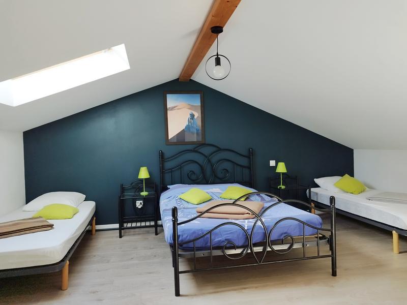 Une chambre avec un lit double et deux lits simples.