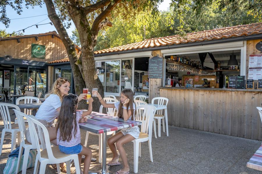 Une femme et deux petites filles trinquent sur la terrasse de l'espace bar / restaurant.