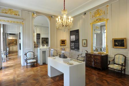 Salle d’exposition du musée du Nouveau Monde à La Rochelle, présentant des œuvres et objets d’art dans un décor du XVIIIᵉ siècle avec moulures dorées et parquet.