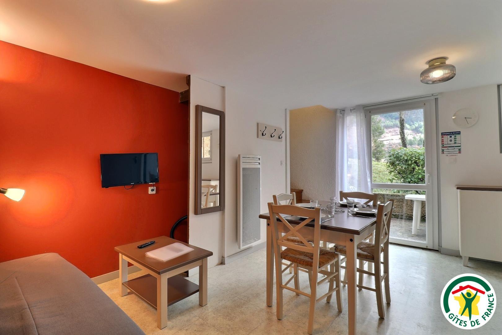 Pièce à vivre avec canapé convertible, espace repas, accès à la terrasse