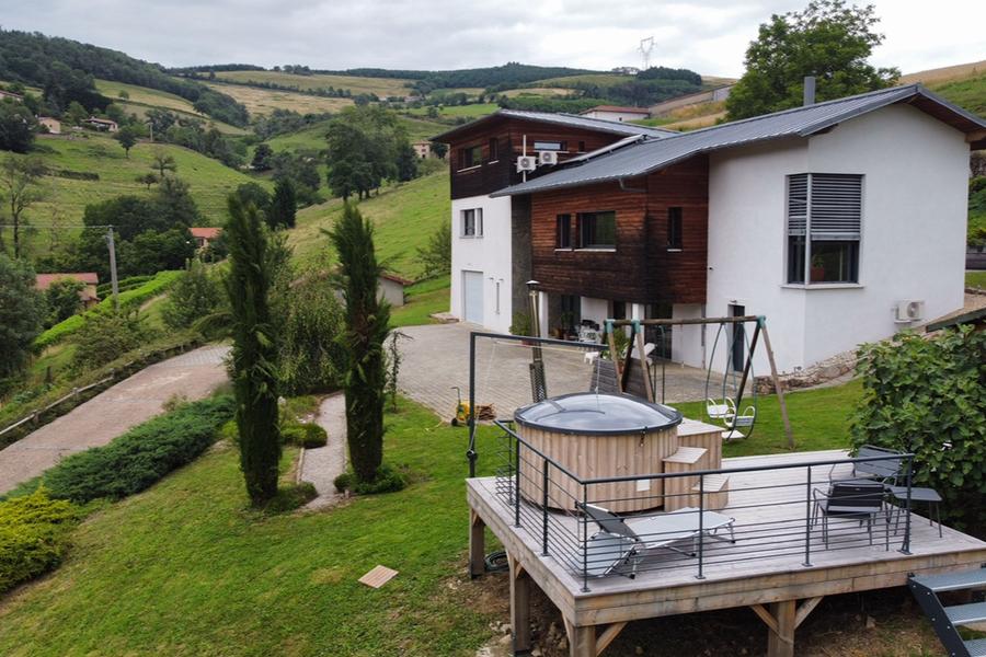 Vue du verger sur la maison avec la terrasse du bain nordique