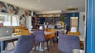 La salle du restaurant vide, avec des tables et chaises.