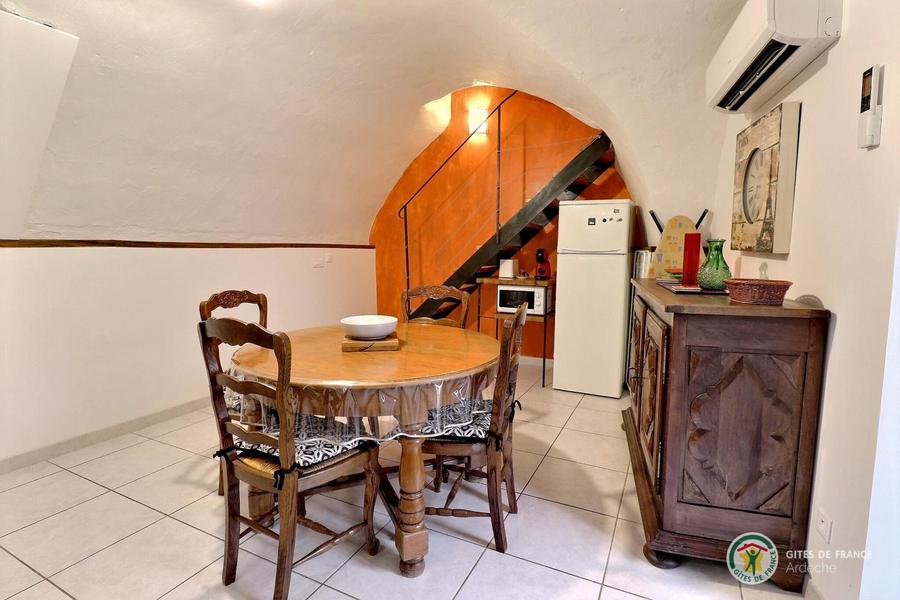 Pièce de vie avec cuisine équipée, table ronde pour les repas et accès terrasse