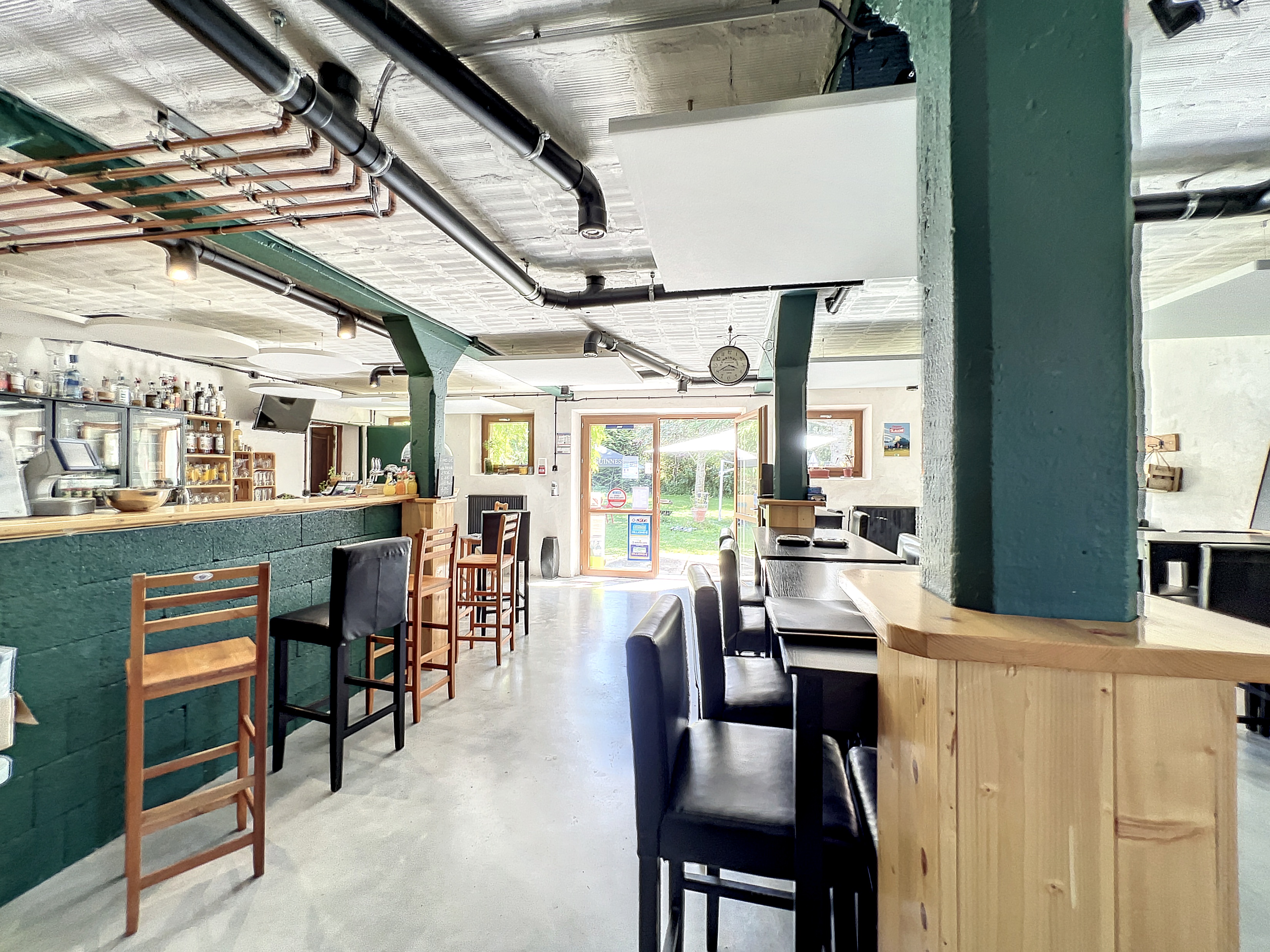 A gauche de la photographie, le bar. Au fond la porte extérieur ouvrant sur le parc. A droite, une partie de la salle.