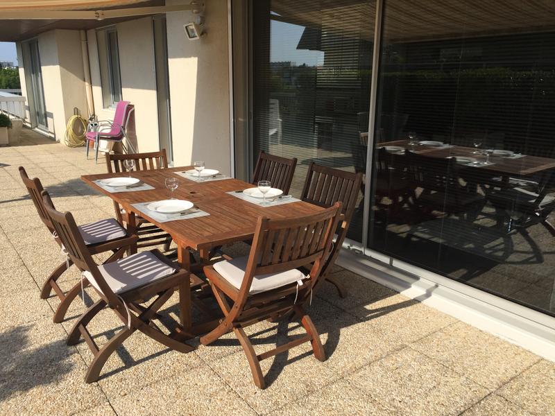 La table en bois dressée pour 4 personnes sur le balcon.