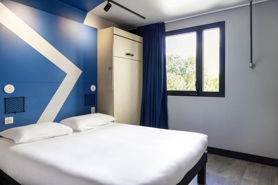 Une chambre avec un lit double, une armoire.