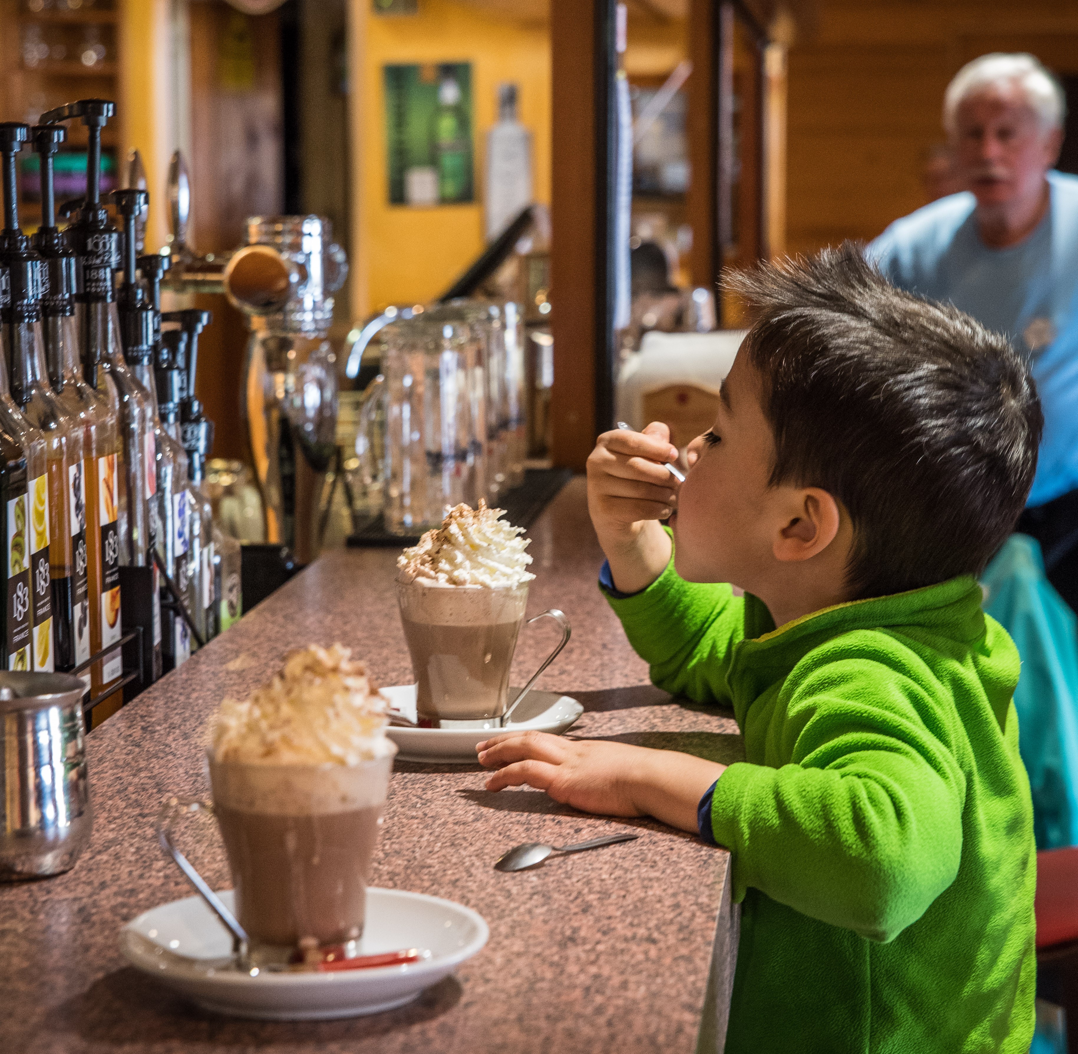Un enfant goûte un chocolat chaud au bar