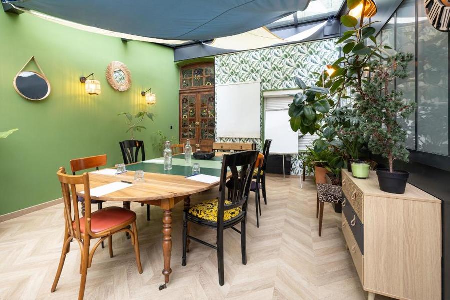 Une salle de séminaire avec une table,  7 chaises, un buffet avec des plantes dessus.