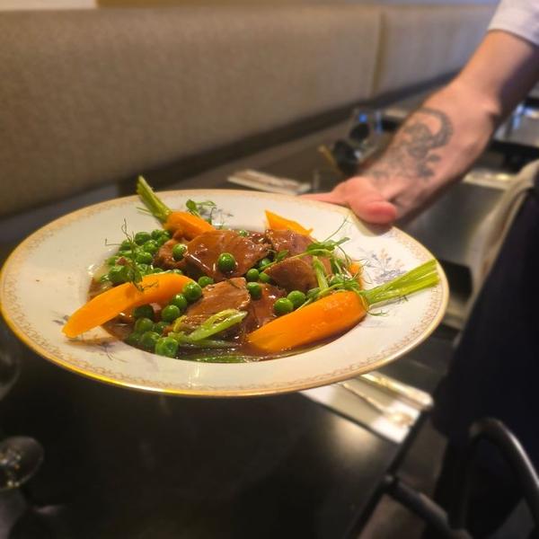 Une assiette avec viande, petits-pois et carottes.