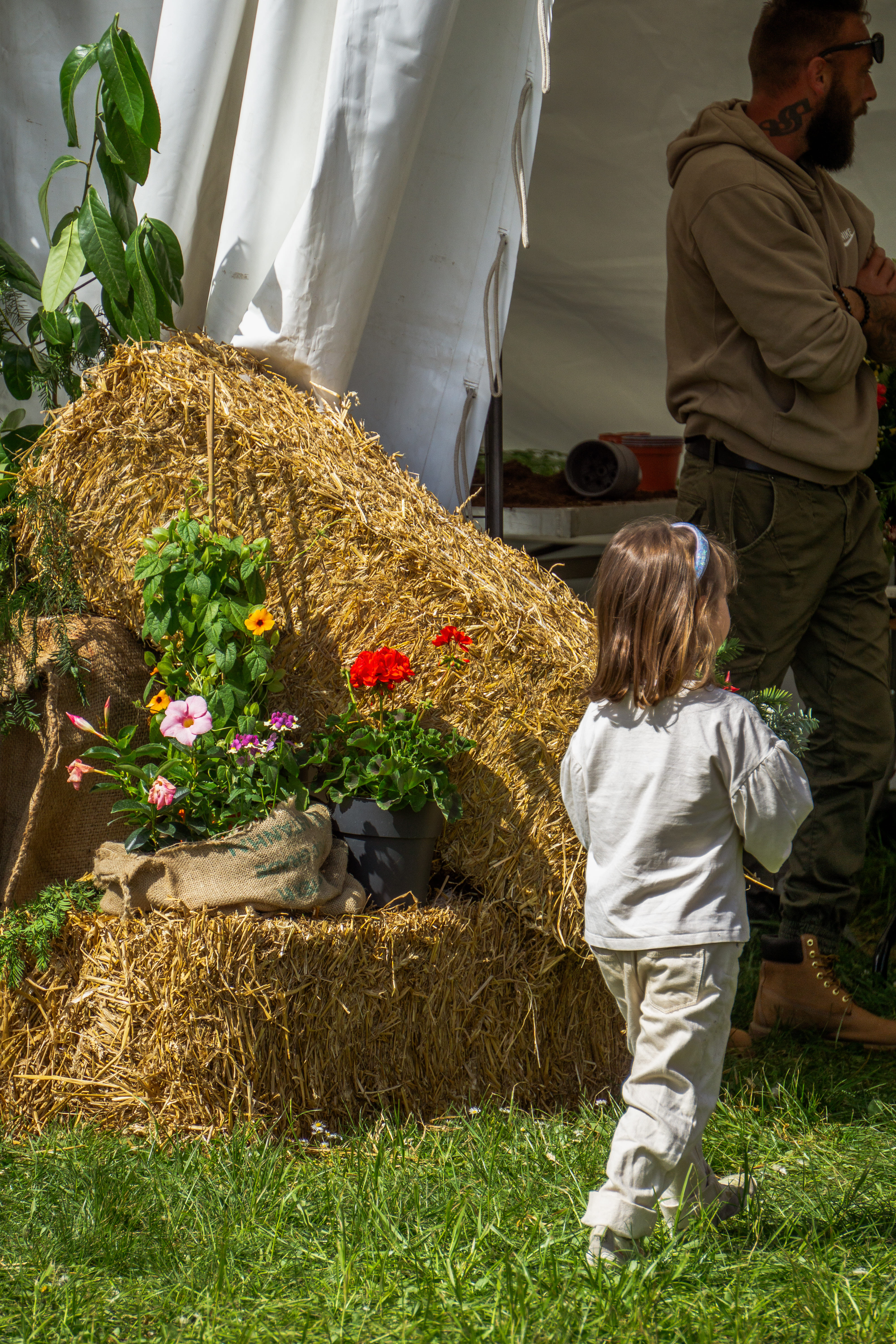 Une petite fille de dos, devant une botte de paille