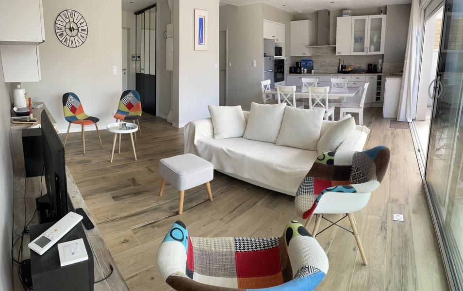 La pièce de vie avec coin salon (canapé, télévision, fauteuill, chaises)