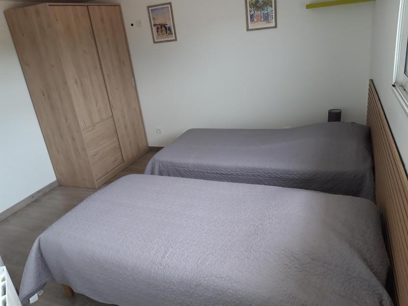 Chambre avec deux lits simples et une armoire.