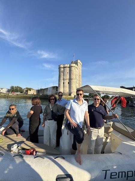 Des passagers sur un bateau à l'arrêt, dans le port, devant les Tours de la Rochelle.