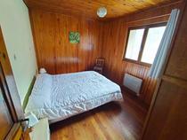 Chambre à coucher lumineuse avec lit double, intérieur bois, ameublement bois, fenêtre