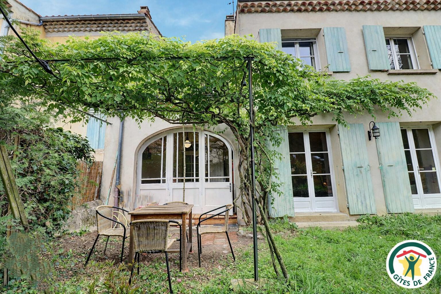 La terrasse avec salon de jardin.
La photo ayant été prise en hiver, le feuillage de la glycine a été réalisé avec l'aide de l'IA.