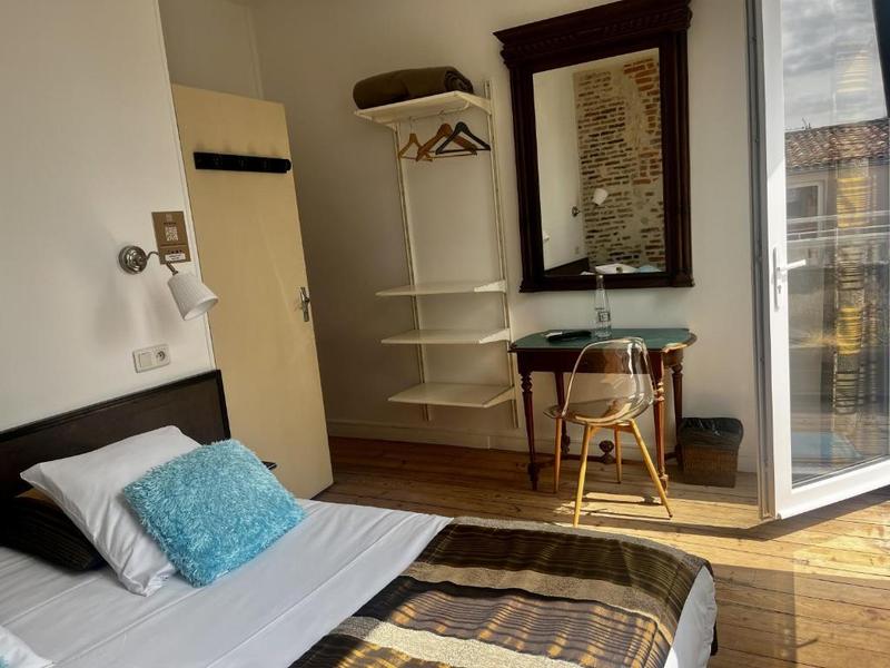 Une chambre avec un lit double, une porte vitrée est ouverte.