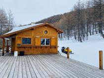 Vue de la cabane du restaurant, sur sa terrasse en bois. Paysage enneigé et moto-neige