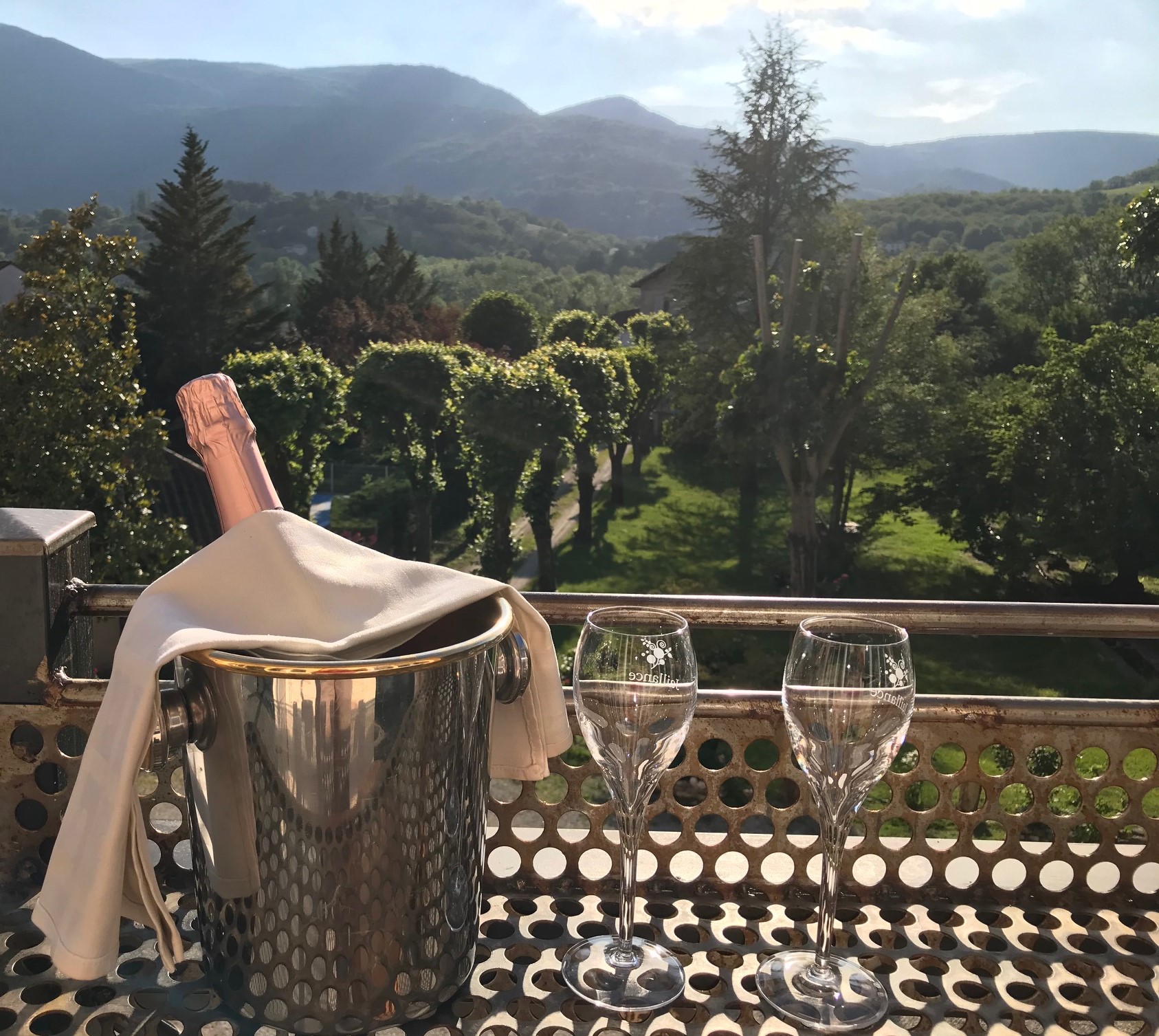 Une bouteille de Clairette dans un seau avec deux verres à Champagne en fond de panorama