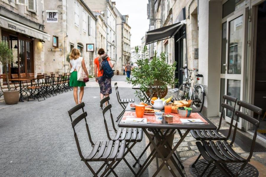 Une petit-déjeuner servi sur une table métallique, sur la terrasse dans la rue de l'hôtel.