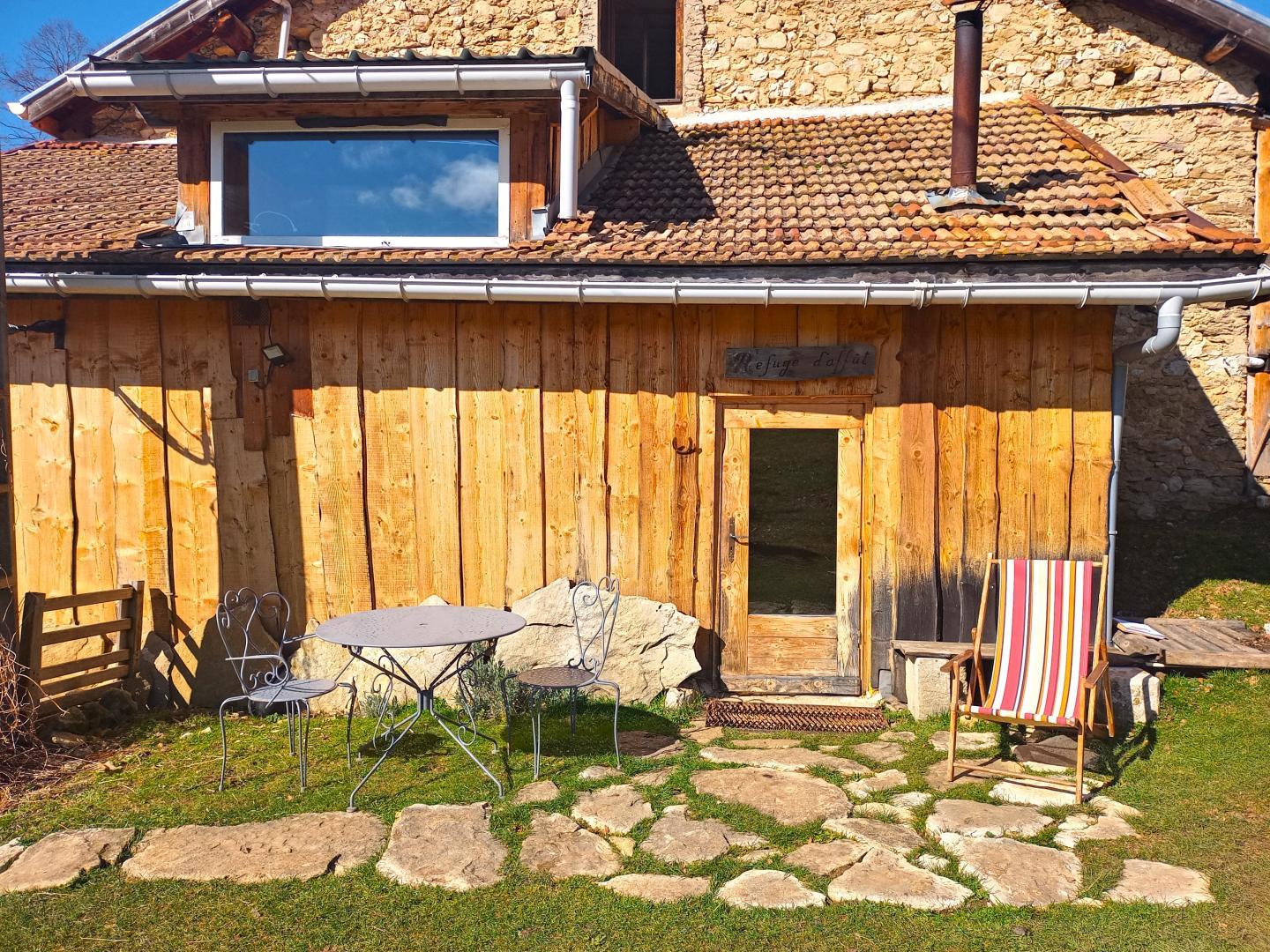 Entrée du gîte et terrasse privative avec vue sur le pré et la forêt