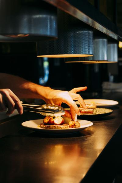 Zoom sur les mains d'un cuisinier dressant une assiette