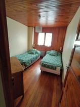 Chambre à coucher lumineuse avec deux lits simples, intérieur bois et lambris, fenêtre