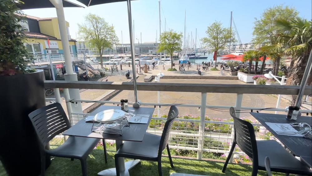 Deux tables sur la terrasse ayant vue sur le bassin des chalutiers.