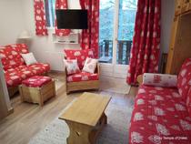 Séjour de studio lumineux avec canapé, fauteuils, TV murale, fenêtre donnant vers un balcon