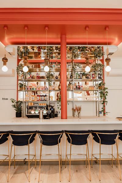 L'espace bar, avec un mur de bouteille et de décoration à l'arrière, des chaises hautes devant le bar.