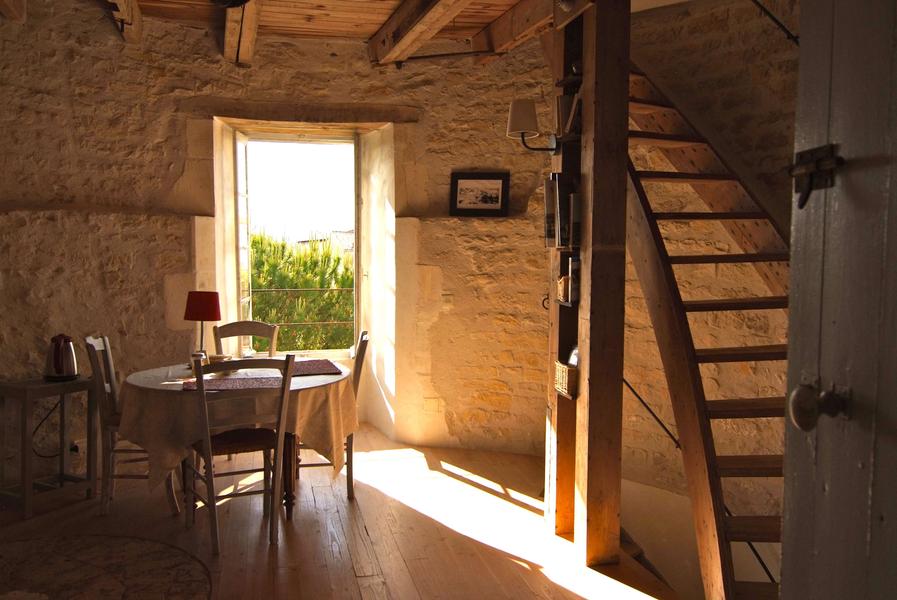 Une pièce dans la tour du moulin, avec une table et un escalier.
