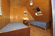 Chambre à coucher lumineuse sous combles avec deux lits simples, fenêtre velux, ameublement bois, intérieur bois