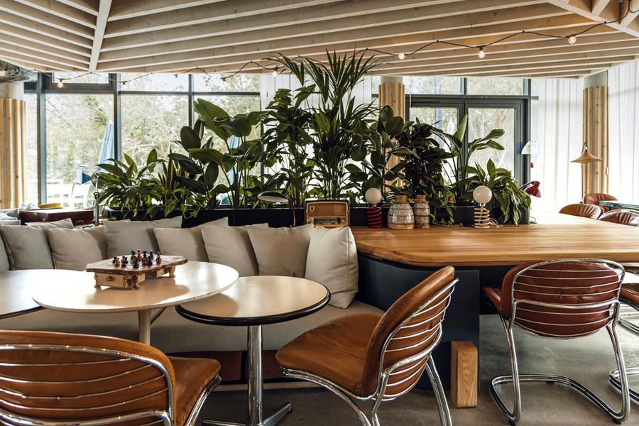 Un espace commun avec des tables, chaises et une large banquette.