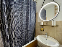 Lavabo avec tablette et miroir au-dessus, rideau de la douche tiré