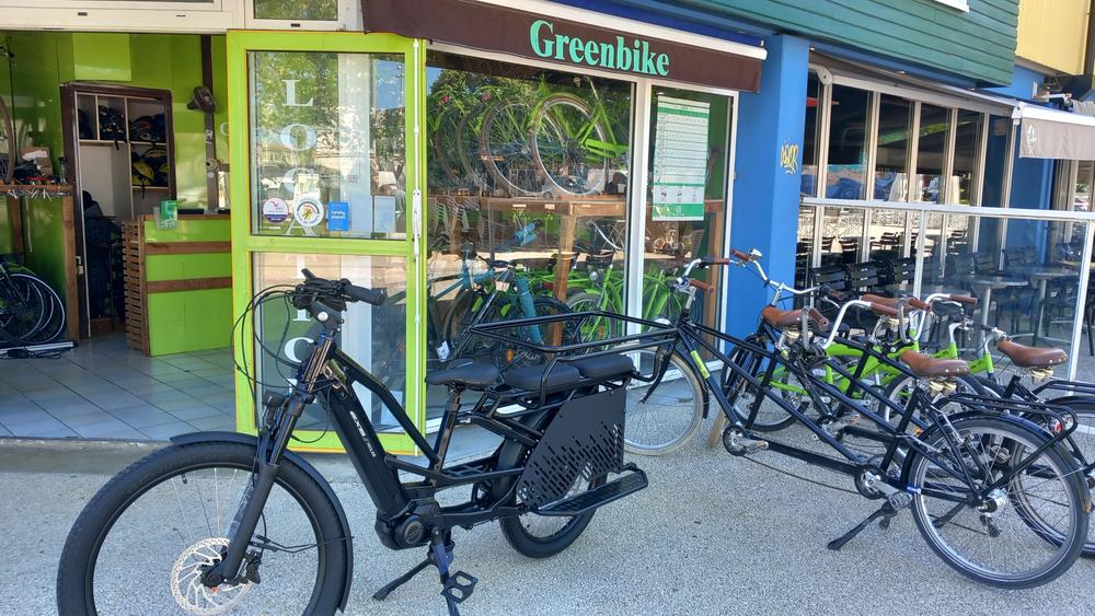 Un vélo cargo, un tandem et des vélos classiques devant la boutique.