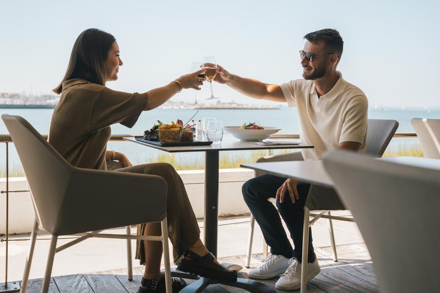 Un couple trinquant en terrasse.