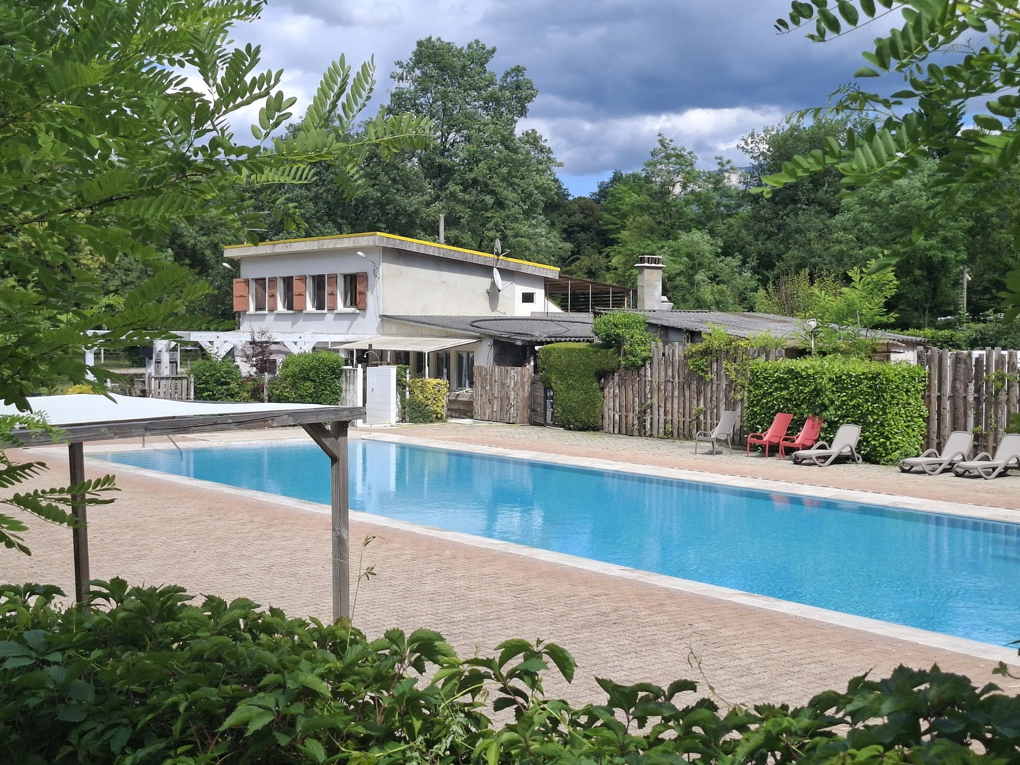 Piscine extérieure entourée d'un espace détente avec transats au cœur du camping