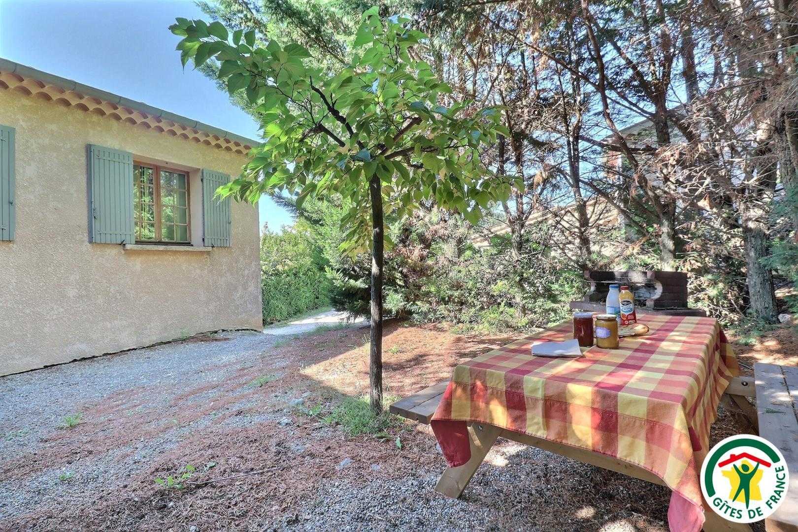 Cour arborée avec table de pique-nique en bois et barbecue
