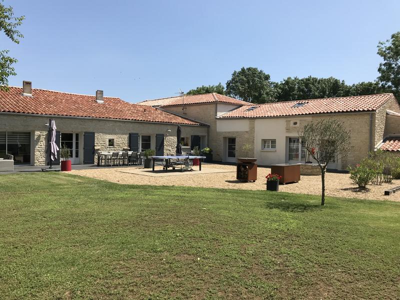 Arrière de la maison vue du jardin, terrasse avec table de ping-pong