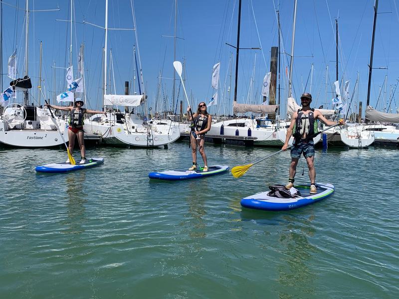 Deux femmes et un homme, chacun sur un paddle, dans le Port.