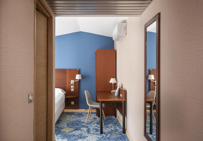 Une chambre vue depuis son couloir, un bureau, une chaise,, on apperctoi un bout du lit.