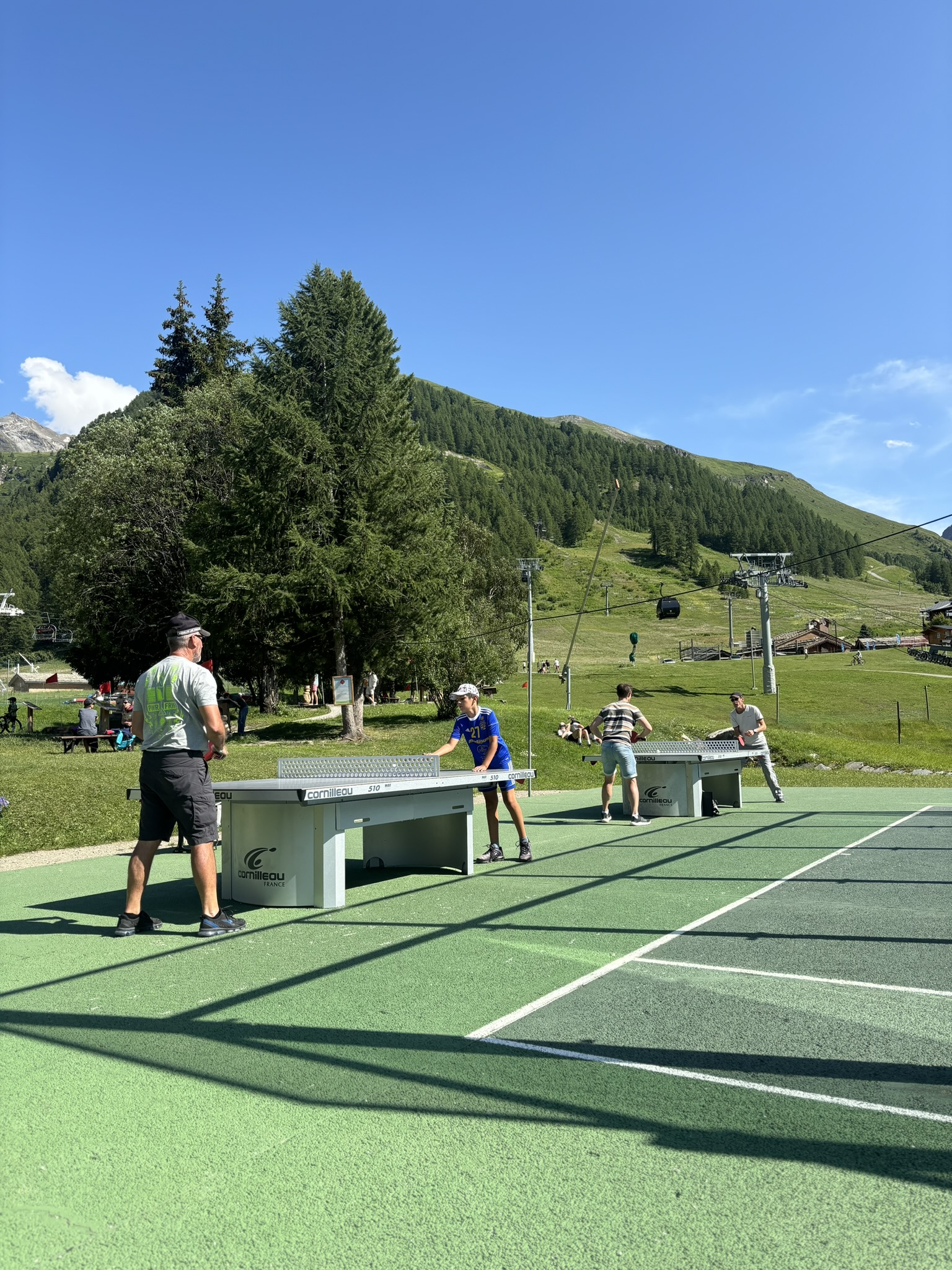 Famille et amis qui jouent au ping pong à Val d'Isère en été