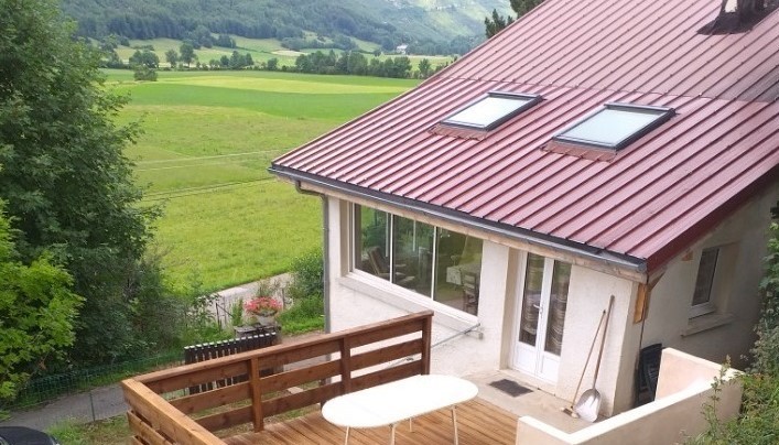 La maison vue du jardin surplombant la terrasse en bois